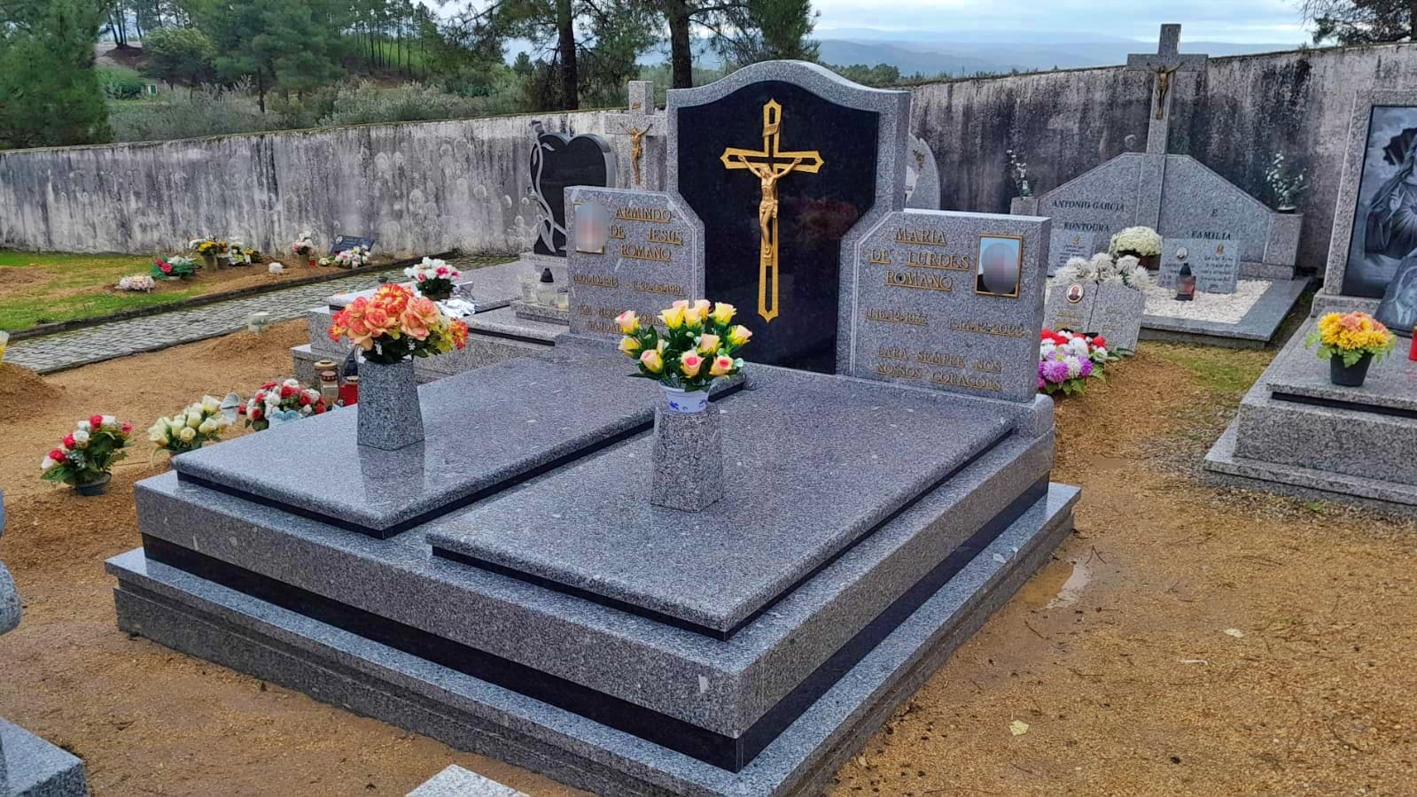 Jazigo duplo em granito cinza com cruz dourada e pedra preta decorativa